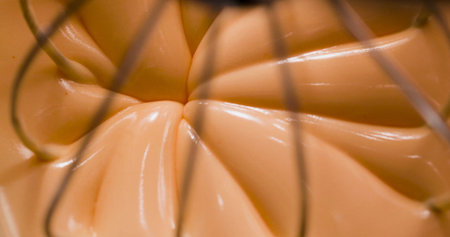 Mixing cream in a bowl with a whisk in a kitchen during the daytime for baking purposesの写真素材