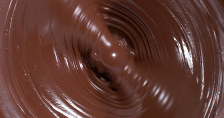 Swirling chocolate in a bowl during the preparation of desserts in a kitchen
