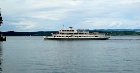 Boat sails on calm water near shore in a scenic area during daytime