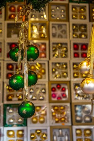 Christmas baubles hanging in front of a variety of blurry boxes with Christmas baubles on a German Christmas marketの写真素材