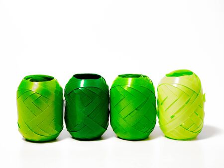 four rolls of ribbon for decorating gifts in different green colours in front of  a white backgroundの写真素材