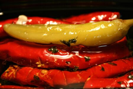 red and green chillies with cheese filling and herbs in olive oilの写真素材