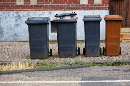 Garbage bins in different colors filled to overflowing as a sign for an affluent societyの写真素材