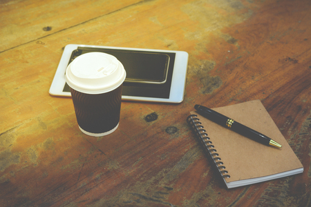 smart phone, tablet, note book, pen and coffee on wooden tableの写真素材