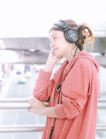 Cute, pretty and beautiful girl with soft focus enjoy music with her headphone in the city with copy spaceの写真素材