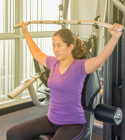 Aisa woman concentrate enjoy sport machine in fitness club with yellow light of sun