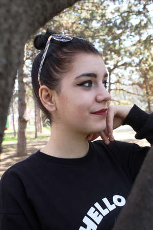 Portrait of a young girl behind a tree outside
