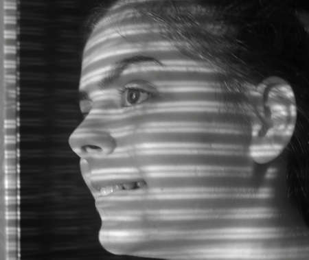 Close-up of a young girl's face looking out the windowの写真素材