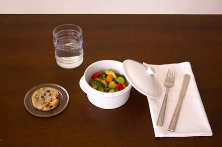 Main course dish, chicken with vegetables, bread, water knife, fork and towelの写真素材
