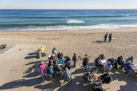 BARCELONA,SPAIN-NOVEMBER 24,2015: Barceloneta beach, a group of people playing cards on an autumn morning, Barcelona.のeditorial素材
