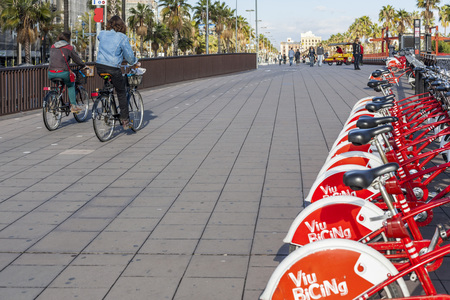 BARCELONA,SPAIN-NOVEMBER 11,2015: Bikers and row of public rental cycles in Port Vell area, Barcelona.のeditorial素材
