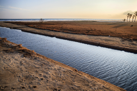 Mediterranean beach and canal at sunset in Vilanova i la Geltru, Catalonia, Spain.