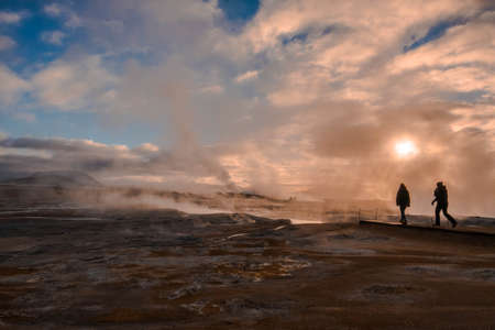 Two tourists amid the water vapor produced by the chimneys of Hverir in Icelandの写真素材