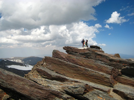 Two people at the top of high red rocky mountainの写真素材