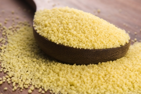 couscous in wooden spoon on kitchen tableの写真素材