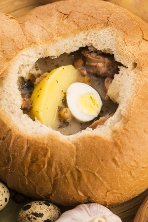 traditional white borscht (zurek) with sausage,egg and mushrooms in bread as bowlの写真素材