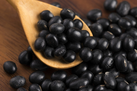 A lot of black soybeans on wooden backgroundの写真素材