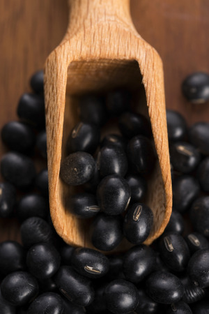 A lot of black soybeans on wooden backgroundの写真素材