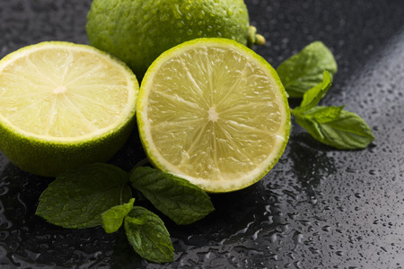 Green limes with mint and water drops on black backgroundの写真素材