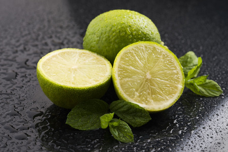 Green limes with mint and water drops on black backgroundの写真素材