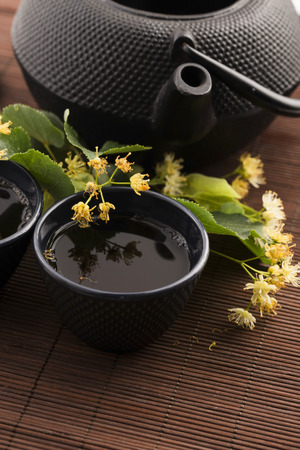 teapot and cup with linden tea and flowersの写真素材