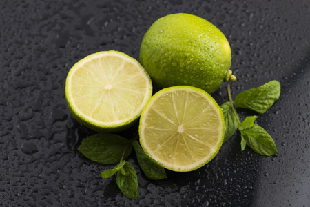 Green limes with mint and water drops on black backgroundの写真素材