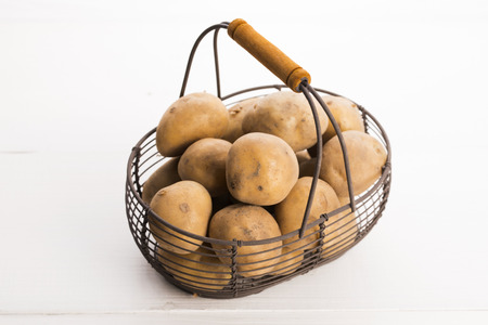 uncooked potatoes in wire basketの写真素材