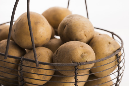 uncooked potatoes in wire basketの写真素材