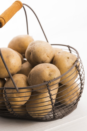 uncooked potatoes in wire basketの写真素材