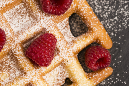 fresh waffles garnished with powdered sugar and raspberriesの写真素材