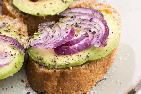 Sandwich with fresh avocado and onion on a plate