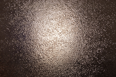 a texture of thick irregular glass with  the bright central partの写真素材