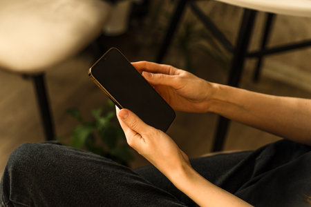 Close-up of hands interacting with a smartphone. The person is holding the device in his hands. The...