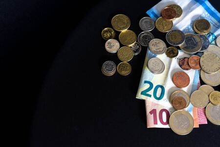 20 and 10 new euro banknote with coins isolated on black background, top view. Empty space on the...