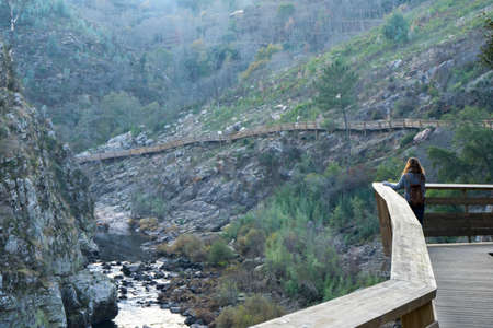 Young girl looking at the landscape on wooden walkways in the mountainsの写真素材