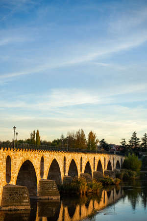 Historical stone bridge over Douro river, sunset hour.