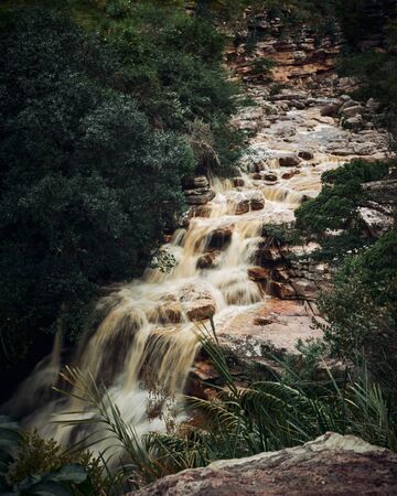 Waterfall on a rocky river, surrounder by green trees in both marginsの写真素材