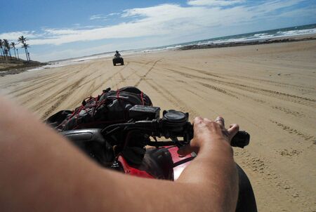 Woman driving quadricycle in the beachの写真素材