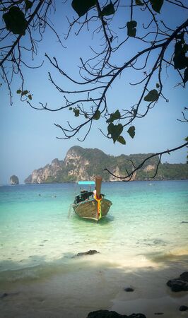 Beautiful Long tail boat in sunset in Railay beach in Krabi province. Ao Nang, Thailland. Framed by leavesの写真素材
