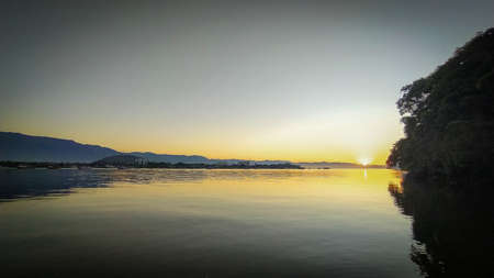 Sunrise sunset at the river "Canal do estuary", between the citys of Guaruja and Bertioga in Brazil. Colorful and serene sunrise at a calm river. Slilhouette of tropical jungleの写真素材