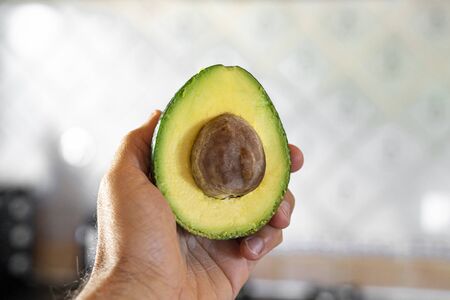 Holding the Avocado in the kitchenの写真素材