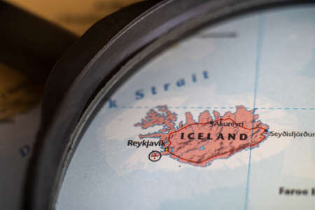 Iceland on a world map through magnifying glass. Iceland travel destination planning pinnedのeditorial素材