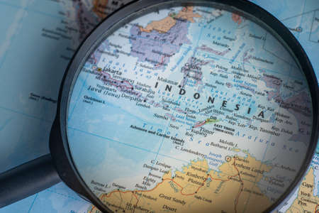 Indonesia on a world map through magnifying glass. Indonesia travel destination planning pinnedのeditorial素材