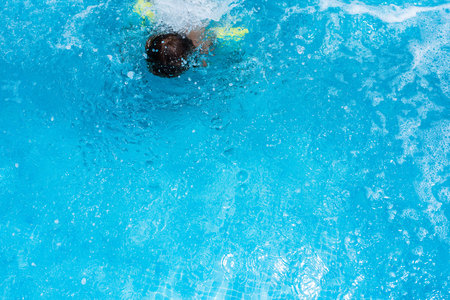 Child splashing in the cool water of a pool in summerの写真素材