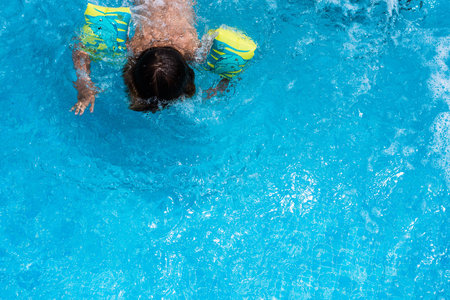 Child splashing in the cool water of a pool in summerの写真素材