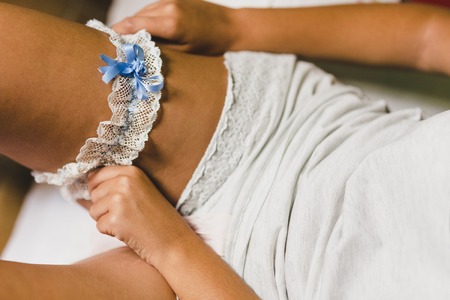 Bride preparing for her wedding, putting on the garter and lingerieの写真素材