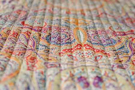 close up from the fabric of a blanket of colors and floral motifs