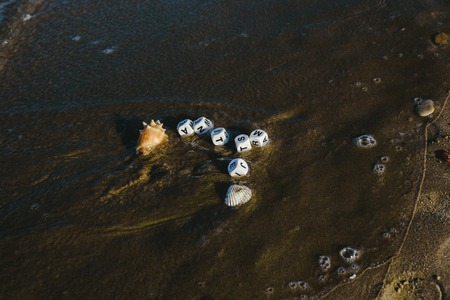 Summer concept made with dice with letters on the wet sand of a beach and marine motives.