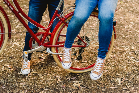 Couple of lovers with green sneakers and jeans standing next to a vintage bicycle