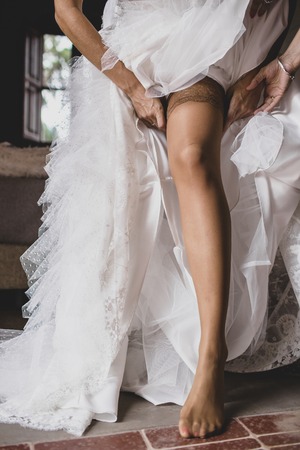 Bride preparing for her wedding, putting on the garter and lingerieの写真素材